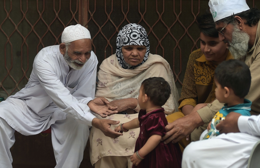 Pakistani national Mohammad Fadhl Akram (L), 73, and his wife Saghran Bibi (2nd L), 62, who fled Syria's war-torn Eastern Ghouta, chatting with relatives in Gihal Zer village, near Sarai Alamgir in Pakistan's eastern Punjab province. — AFP