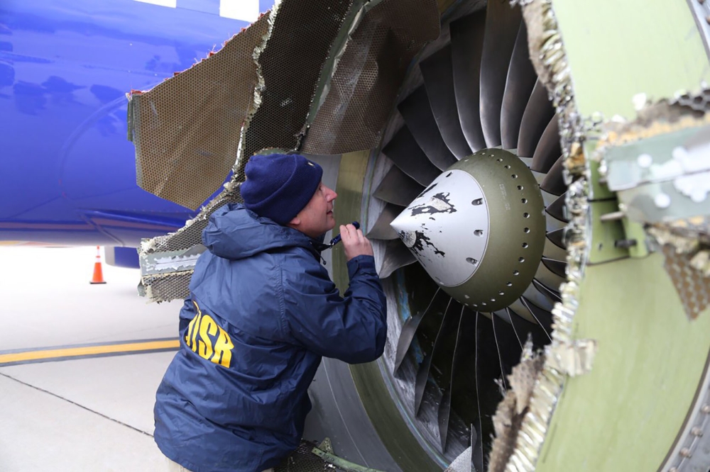 A National Transportation Safety Board investigator examines damage to the engine of the Southwest Airlines plane on Tuesday.  — AFP