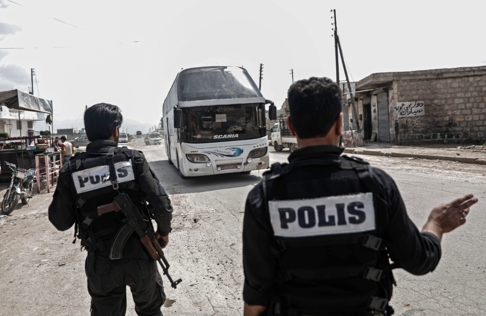 A picture taken in the Syrian city of Azaz in the northern countryside of Aleppo shows members of the Turkish-backed Syrian rebel police directing buses carrying evacuees from Dumayr, a town lying east of Damascus further from Eastern Ghouta where a reconciliation agreement had kept a security status quo since 2016 until it was retaken by government forces the day before. A convoy of 31 buses was carrying about 1600 of fighters and civilians arrived in Azaz, while most of the buses headed to Afrin.  — AFP