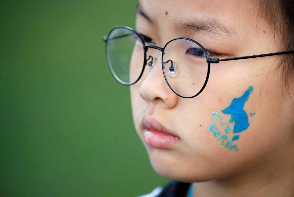 A blue silhouette of the Korean peninsula, which is used in the unification flag, is seen on a girl’s face during a rally to wish a successful inter-Korean summit, in central Seoul, South Korea, on Saturday. — Reuters