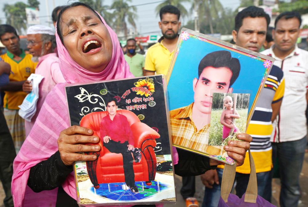 A family member of deceased garment workers cries as she holds photos of beloved ones in front of the Rana Plaza building site during a memorial ceremony marking the fifth anniversary of the collapse of the nine-story building on the outskirts of Dhaka, Bangladesh, on Tuesday.  — APA