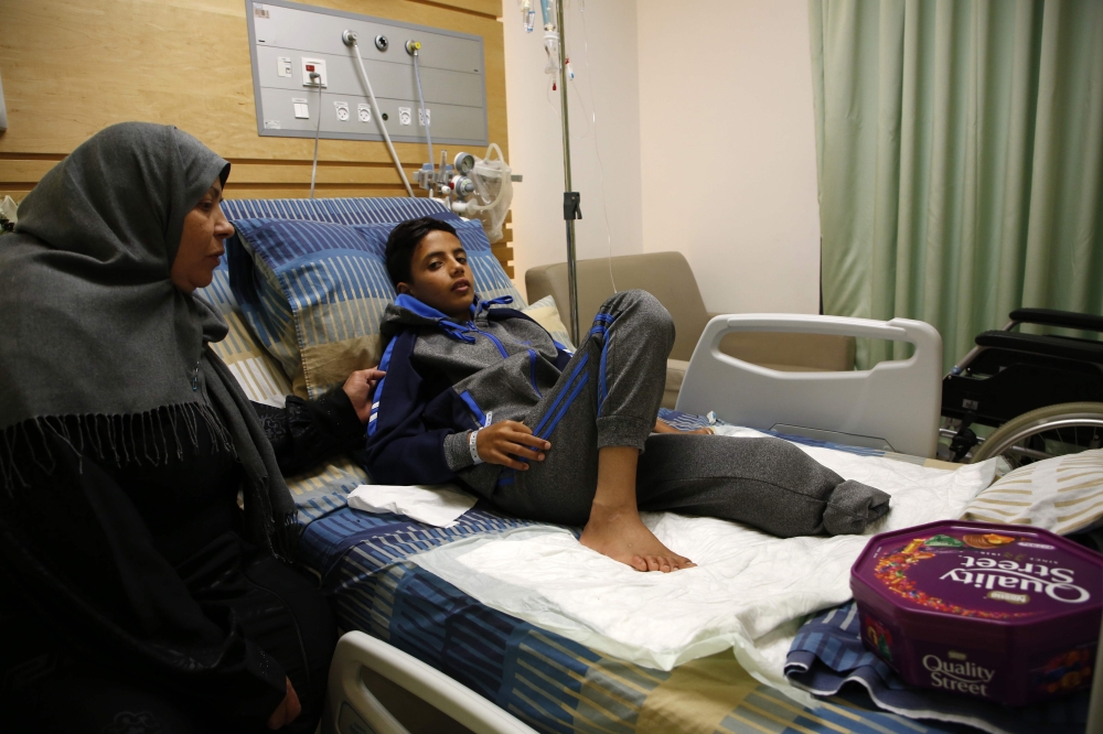 Abdel Rahman Nawfal, 12, sits next to his grandmother in a hospital in the West Bank city of Ramallah after his leg was amputated following an injury sustained from bullets fired by Israeli forces near the Gaza-Israel border.  — AFP