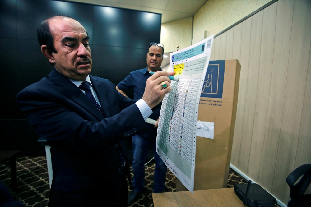 The head of Iraq's Independent Higher Election Commission Dr. Riyhad Al-Badran demonstrates the new voting method in Baghdad. — Reuters