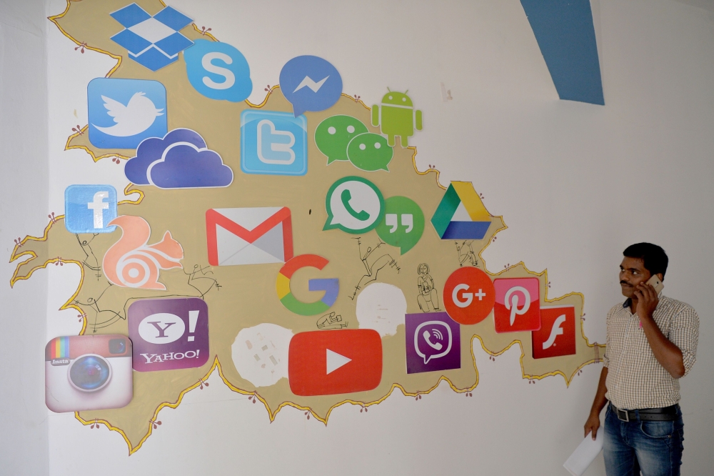 In this file photo taken on March 22, 2018, an Indian visitor passes a mural depicting various social media companies including Facebook and Twitter inside a building in Bangalore, India. - AFP