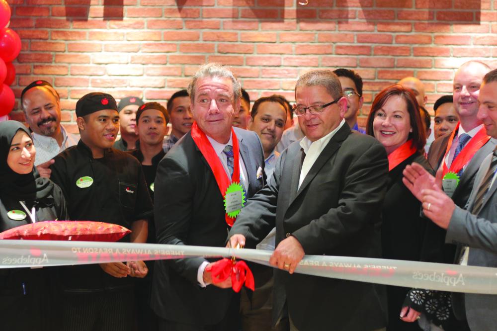 Steve Joyce, chief executive officer of Applebee’s parent company Dine Brands Global Inc., cuts the ceremonial ribbon with the help from officials from Arabian Entertainment 
