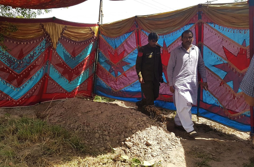 Pakistani policemen walk beside the grave of Italian national of Pakistani origin Sana Cheema, who was allegedly killed by her family members, in Gujrat of Pakistan’s Punjab province on Wednesday. — AFP