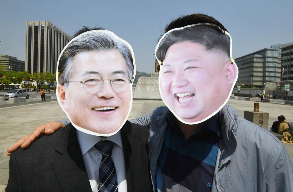 South Korean activists wearing masks of South Korean President Moon Jae-in, left, and North Korean leader Kim Jong Un, right, pose for a photo during a rally to support the upcoming inter-Korean summit, at Gwanghwamun square in Seoul on Wednesday. — AFP
