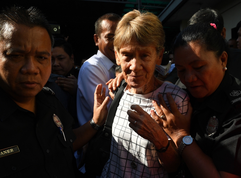 Australian catholic nun Sister Patricia Fox, center, is being escorted by immigration officers while leaving a detention facility after her release at the Immigration headquarters in Manila, a day after she was arrested, in this April 17, 2018 file photo. — AFP