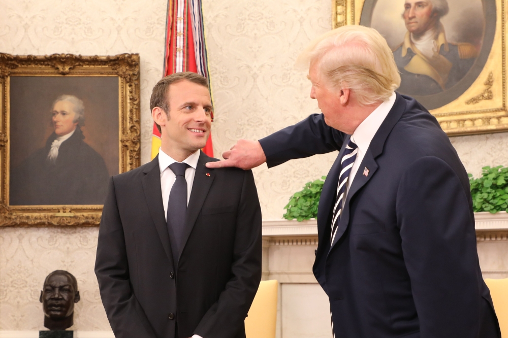 TOPSHOT - US President Donald Trump (R) clears dandruff off French President Emmanuel Macron's jacket in the Oval Office prior to a meeting at the White House in Washington, DC, on April 24, 2018.  / AFP / ludovic MARIN

