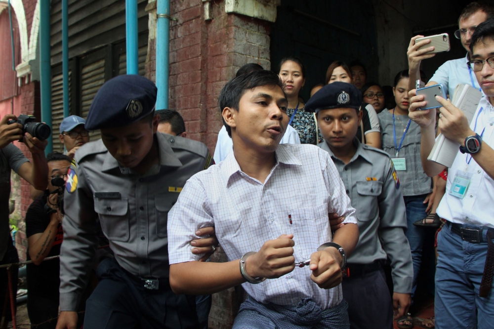 Detained Myanmar journalist Kyaw Soe Oo, center, is escorted by police to a court for his ongoing trial in Yangon on Wednesday. — AFP