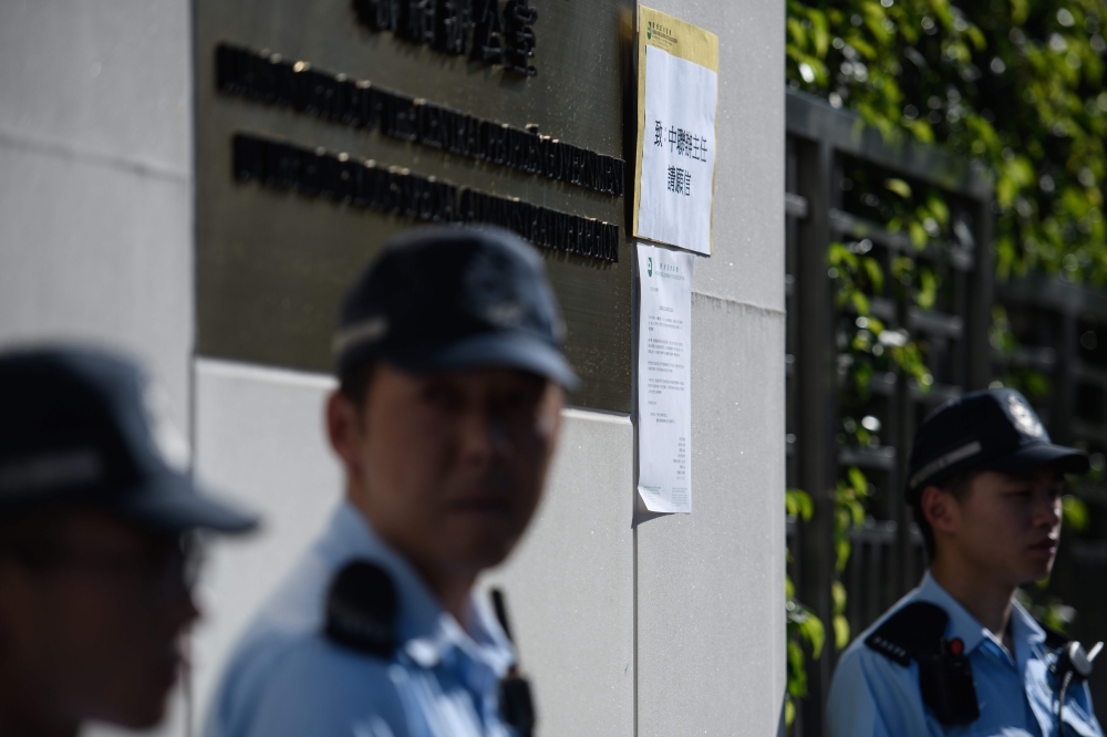 A letter, center, from the Hong Kong Journalist Association (HKJA) is displayed outside the China’s Liaison Office building as police stand guard in Hong Kong on Wednesday, after a Hong Kong journalist was arrested and left injured while trying to interview a human rights lawyer in Beijing. — AFP