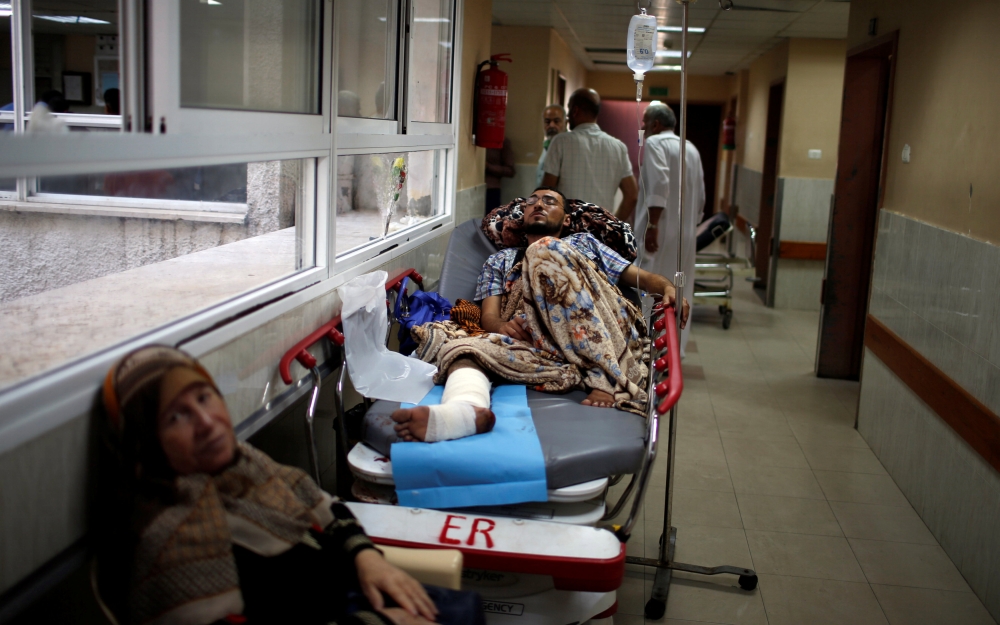An injured Palestinian lies on a bed in the corridor of a hospital in Gaza City. — Reuters