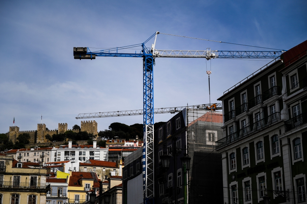A construction crane rises near the Augusta Street Arch in downtown Lisbon. Lisbon's azure skies are dotted with forests of cranes as scores of construction workers give Portugal's capital a shiny and new, if pricey, veneer. For years the local construction industry lay in the doldrums — but those days are gone with the city today a hive of activity, a boon for those involved in its overhaul. — AFP