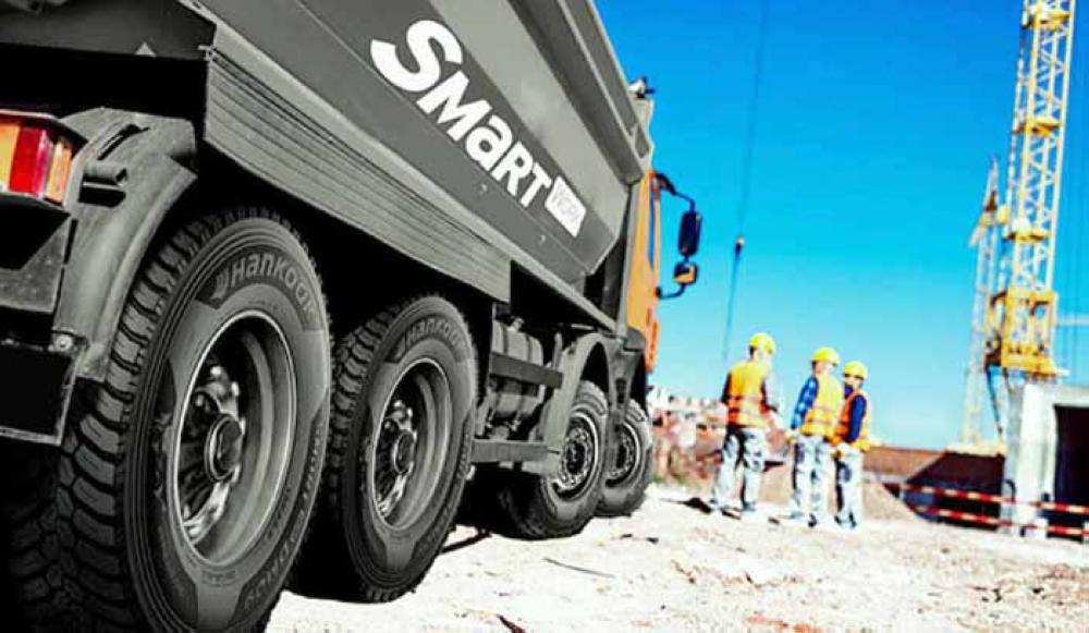 Hankook: Three builders in uniform standing near a big yellow tip truck at construction site
