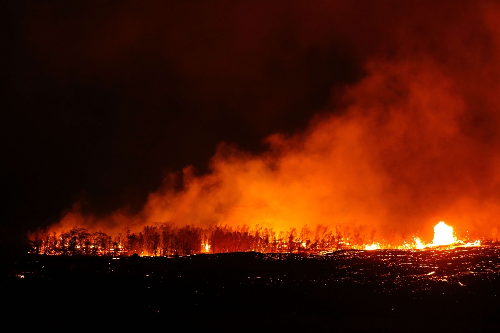 Lava erupts and flows from a Kilauea volcano fissure as trees burn on Hawaii’s Big Island in Kapoho, Hawaii, on Friday. — AFP