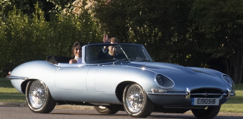 Newlyweds Britain's Prince Harry, Duke of Sussex and Meghan, Duchess of Sussex wave as they leave Windsor Castle by car to attend their reception in Frogmore House on castle grounds, in Windsor on Saturday. - EPA