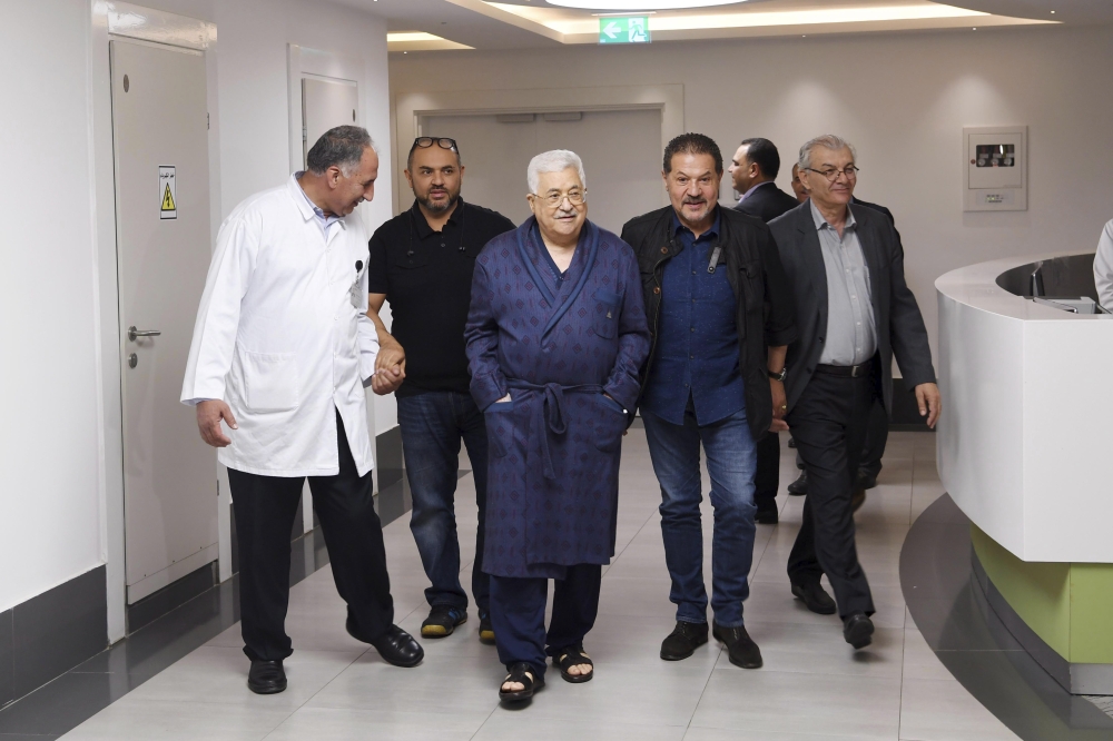 A handout photo made available by the Palestinian President office shows the Palestinian President Mahmoud Abbas (C) surrounded by his sons and his doctors taking a walk at the hospital in Ramallah. — EPA