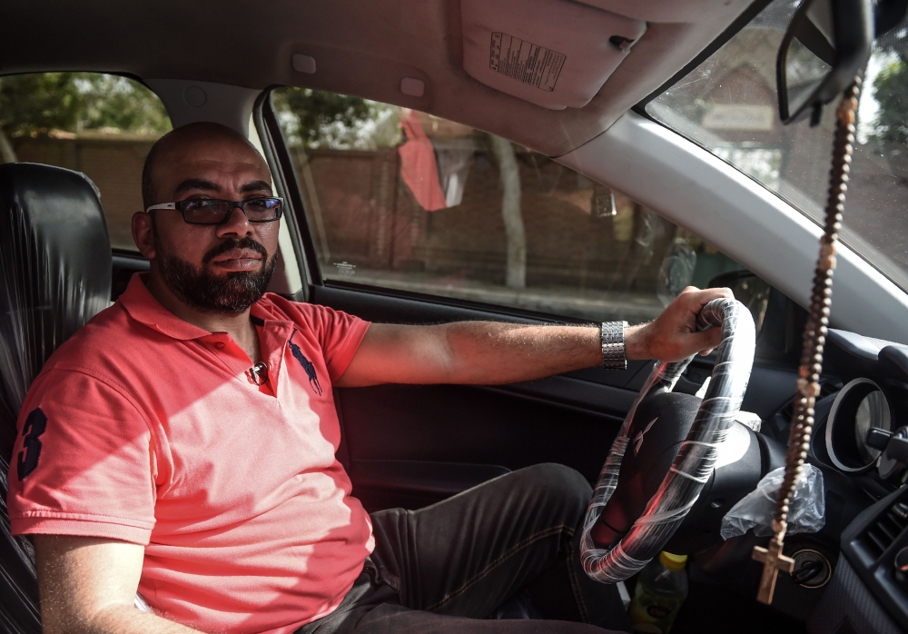 Ramez Wagih, an accountant in the morning and Uber driver in the afternoon, poses in his car in the Egyptian capital Cairo. — AFP