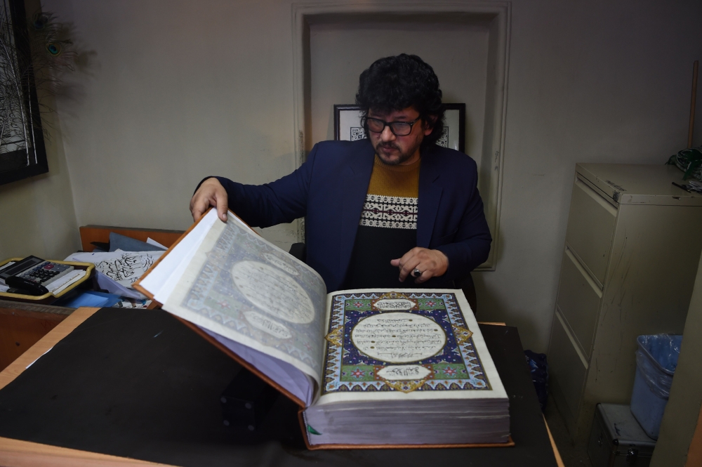 Afghan master miniature artist Mohammad Tamim Sahibzada shows a handmade Qur'an made with silk fabric at the Turquoise Mountain Foundation in Mourad Khani, in the old city section of Kabul. One of the only Qur'an copies ever made from silk fabric has been completed in Afghanistan — a feat its creators hope will help preserve the country's centuries-old tradition of calligraphy.  — AFP photos
 