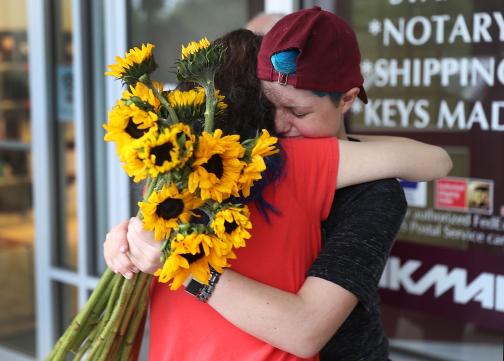 Caspen Becher, right, a freshman at Marjory Stoneman Douglas High School is hugged as she joins with others for a protest in a Publix supermarket in Coral Springs, Florida, on Friday.— AFP