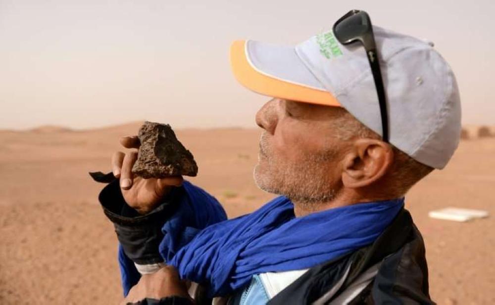 Meteorite hunter Mohamed Bouzgarine examines a rock near the town of M'hamid el-Ghizlane, in southern Morocco. — AFP