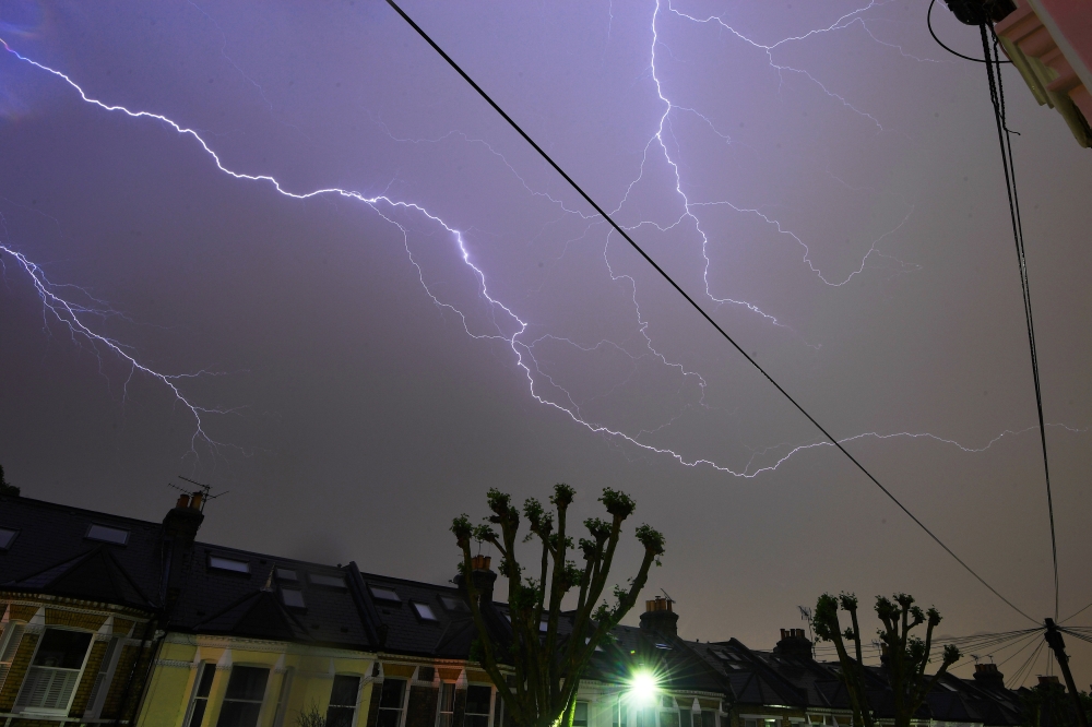 Lightning is seen from a bedroom window as it strikes above a street in south London, Britain, on Saturday night. — Reuters