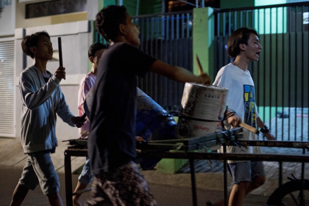 Youths sing and bang on improvised drums as they walk around their neighborhood to wake up residents for Sahoor before the start of the fasting day in Jakarta, Indonesia. - AFP