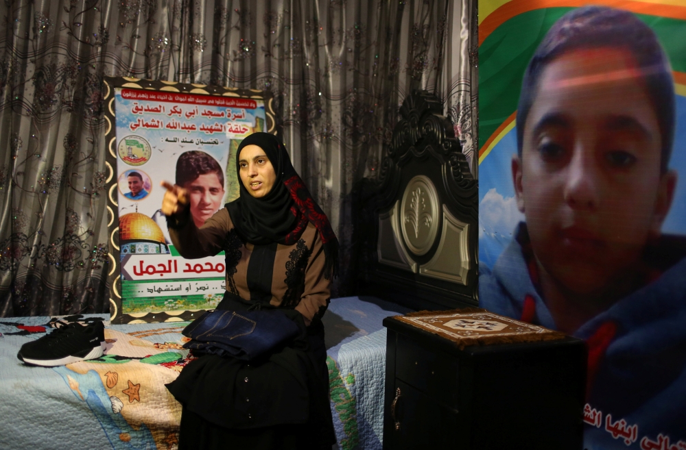 The mother of Palestinian Hiatham Al-Jamal, 15, who was killed during a protest at the Israel-Gaza border, gestures as she shows clothes he bought to wear during Eid Al-Fitr holiday, in Rafah in the southern Gaza Strip, on Thursday. — Reuters