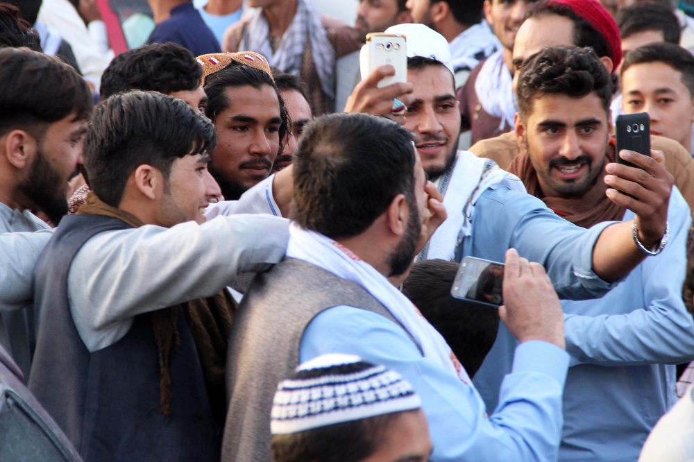 People take a selfie with an alleged Taliban militant as a group of Taliban visit a bazaar to greet people as a goodwill gesture amid a three-day ceasefire on first day of Eid Al-Fitr, in Kunduz, Afghanistan, on Saturday. — EPA