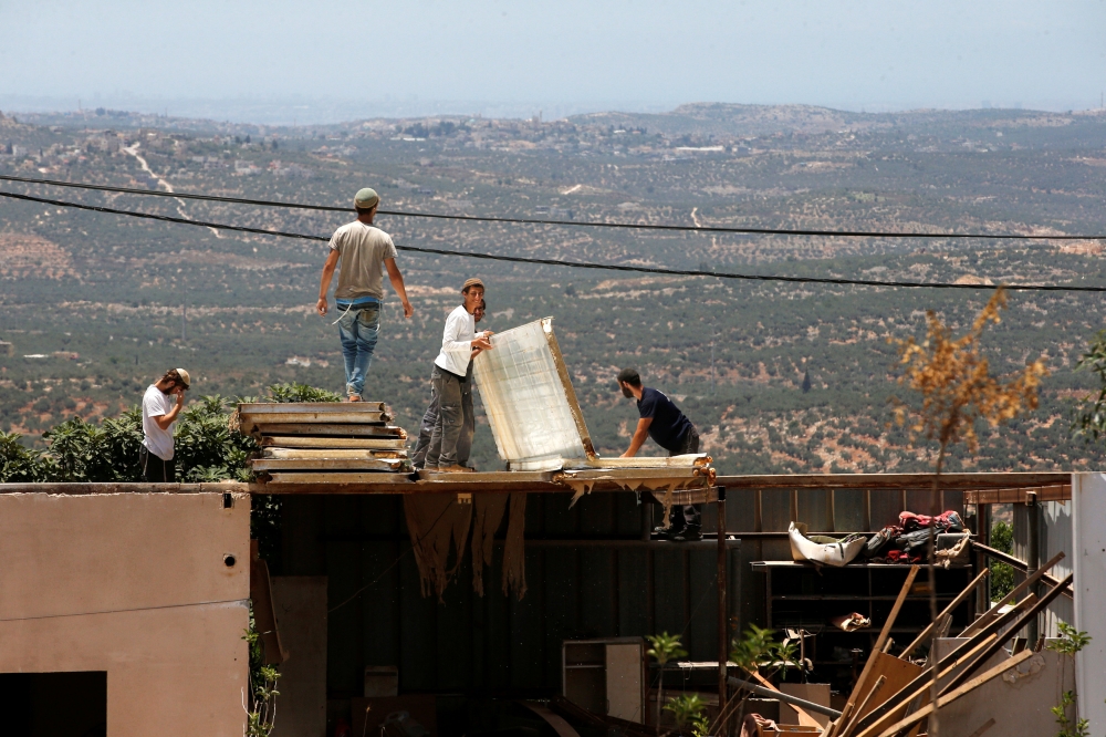 Jewish settlers dismantle parts of a structure during the eviction of buildings that an Israeli court deemed to have been built illegally in Tapuach West settlement, in the Israeli occupied West Bank, on Sunday. — Reuters