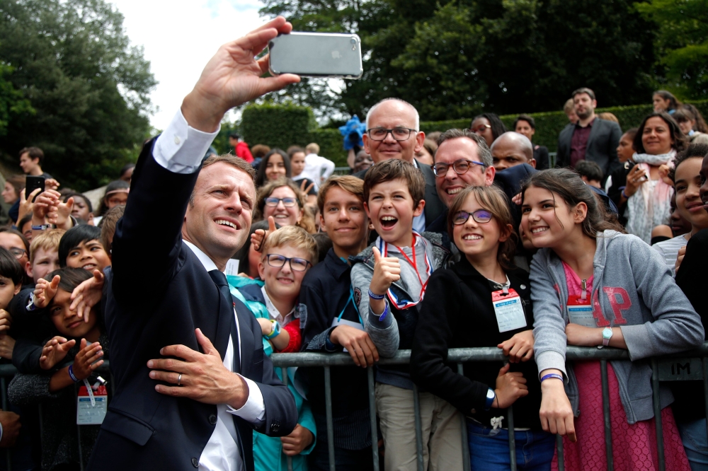 French President Emmanuel Macron (C) takes a 'selfie' with members of the crowd, as he leaves after a ceremony commemorating General Charles De Gaulle's June 1940 appeal for French resistance against Nazi Germany, at the Mont Valerien National Memorial in Suresnes on the outskirts of Paris on Monday. — AFP