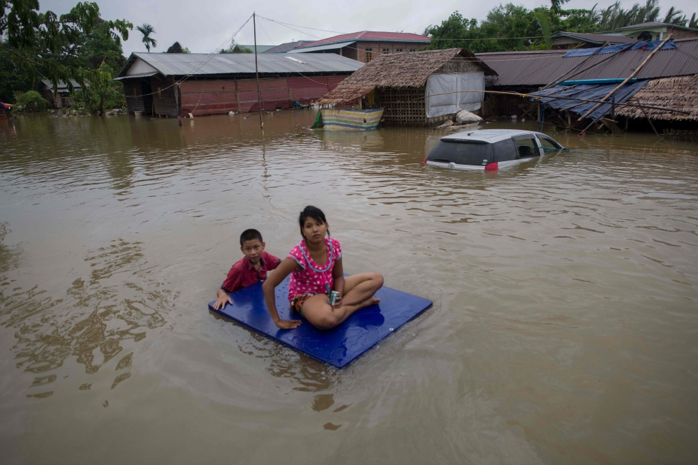 Residents use improvised raft to move around in the flooded township of Mawlamyine district in Mon state, Myanmar, on Monday. — AFP