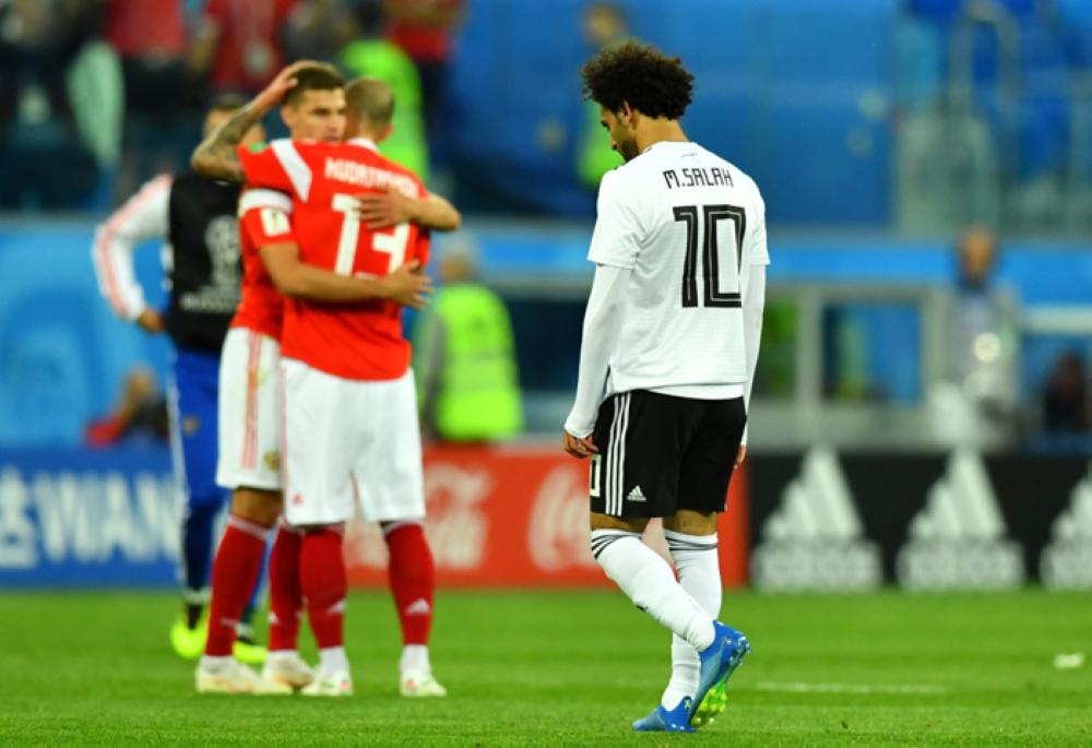 Egypt's Mohamed Salah looks dejected after the match as Russia players celebrate — Reuters