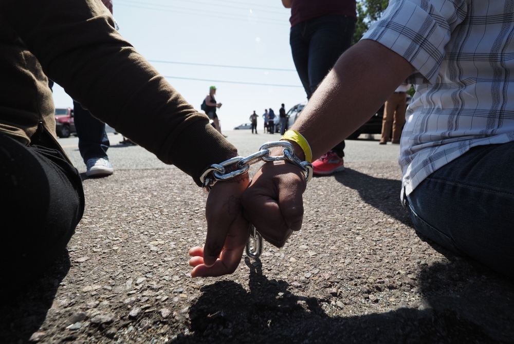Protesters chained together at the wrist block traffic from passing on the road to the Otay Mesa  Detention Center during a demonstration against US immigration policy that separates children from parents, in San Diego, California, on Saturday. — AFP