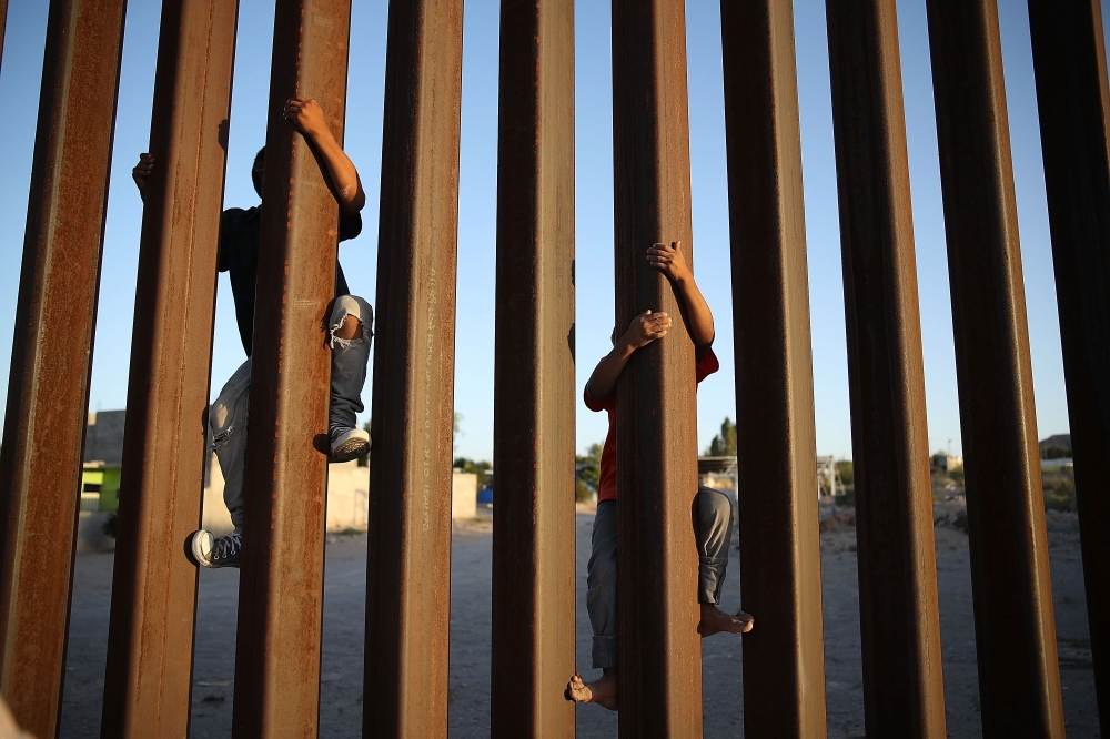Children climb up the Mexican side of the US/Mexico border fence  in Sunland Park, New Mexico, on Sunday. — AFP