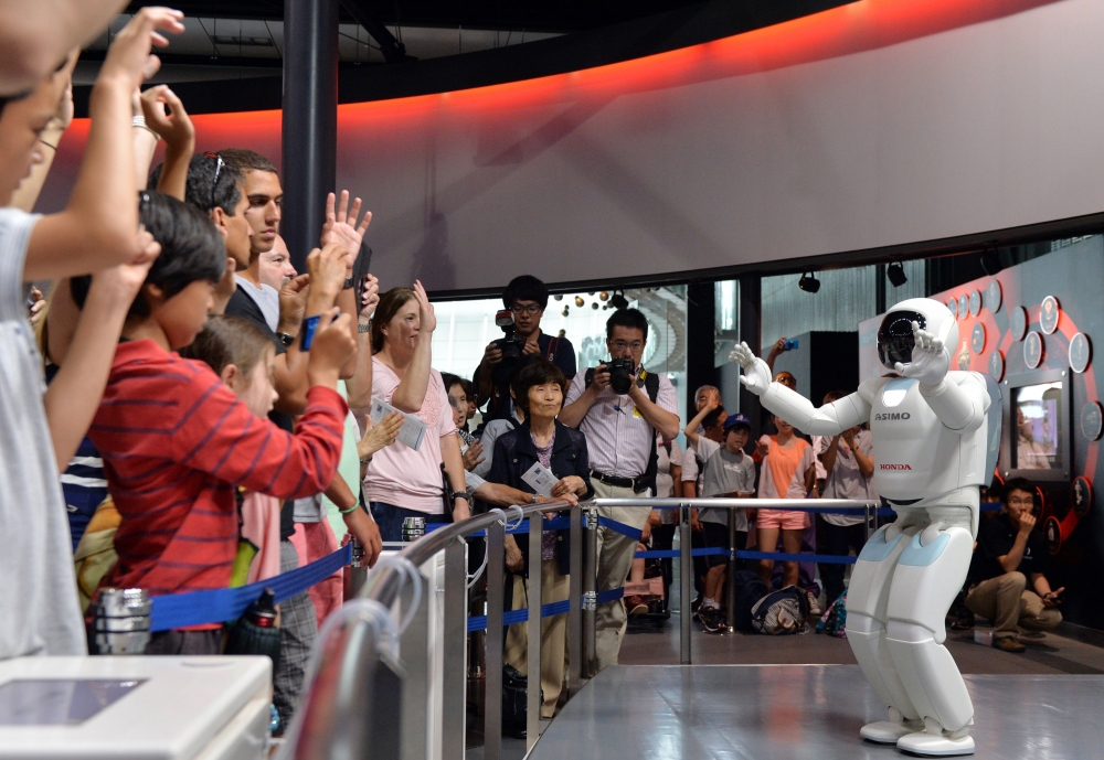 This file picture shows Honda Motor's humanoid robot Asimo interacting with visitors at the National Museum of Emerging Science and Innovation in Tokyo.  Launched in 2000, the humanoid machine resembling a shrunken spaceman has become arguably Japan's most famous robot, wheeled out to impress visiting politicians over the years. — AFP