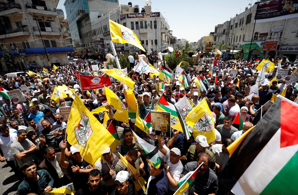 Palestinians take part in a rally in support of President Mahmoud Abbas, in Ramallah, in the occupied West Bank, Monday. — Reuters