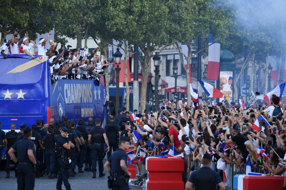 French fans wave French national flag and cheer France's team players as they celebrate on the roof of a bus while parading down the Champs-Elysee avenue in Paris Monday. — AFP