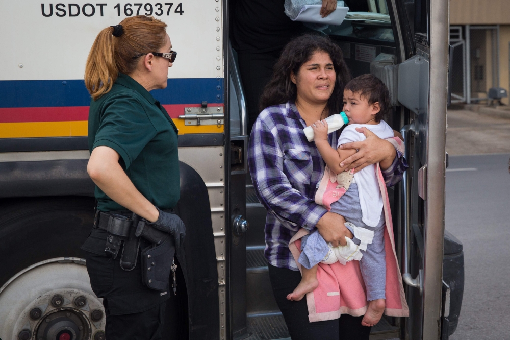 A woman carries a baby as immigrants are dropped off at a bus station shortly after being released from detention through “catch and release” immigration policy in McAllen, Texas, in this June 17, 2018 file photo.  