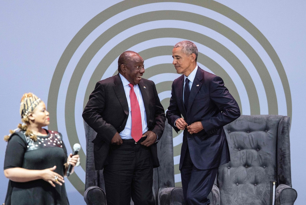 Former US President Barack Obama, right, fastens his vest before dancing on stage with President Cyril Ramaphosa, center, and South African singer Thandiswa Mazwai during the 2018 Nelson Mandela Annual Lecture at the Wanderers cricket stadium in Johannesburg on Tuesday. — AFP