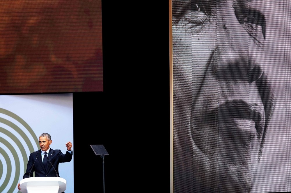 Former US President Barack Obama, right, fastens his vest before dancing on stage with President Cyril Ramaphosa, center, and South African singer Thandiswa Mazwai during the 2018 Nelson Mandela Annual Lecture at the Wanderers cricket stadium in Johannesburg on Tuesday. — AFP