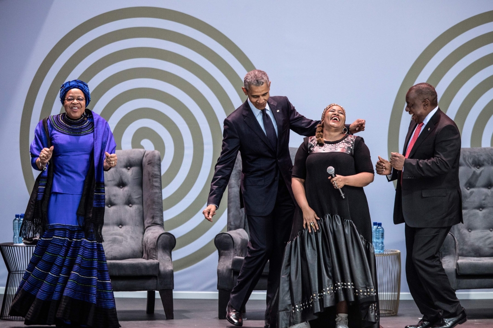 Former US President Barack Obama, right, fastens his vest before dancing on stage with President Cyril Ramaphosa, center, and South African singer Thandiswa Mazwai during the 2018 Nelson Mandela Annual Lecture at the Wanderers cricket stadium in Johannesburg on Tuesday. — AFP