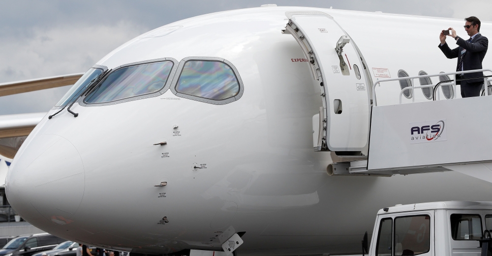 A man takes a photograph as he stands on steps leading into an Airbus A220-300 at the Farnborough Airshow, south west of London, on Wednesday. — AFP