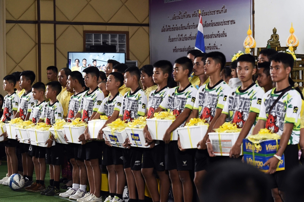 The twelve boys and their football coach, dramatically rescued from deep inside a Thai cave after being trapped for more than a fortnight, hold boxes of gifts after a press conference in Chiang Rai on Wednesday, following their discharge from the hospital. — AFP