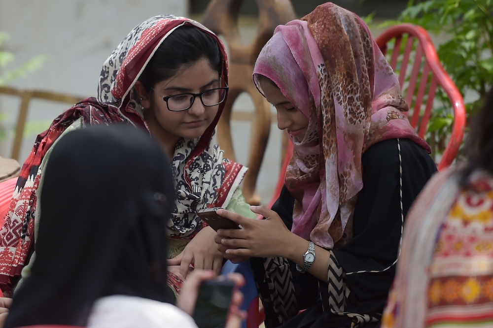 Students use their mobile phones at a campus in Islamabad. A titanic 46 million people below the age of 35 are registered to vote in nationwide elections on July 25 — many of them savvy social media users who are utilizing platforms such as YouTube and Facebook Live to undermine traditional voting patterns by posting videos calling out the powerful. — AFP
