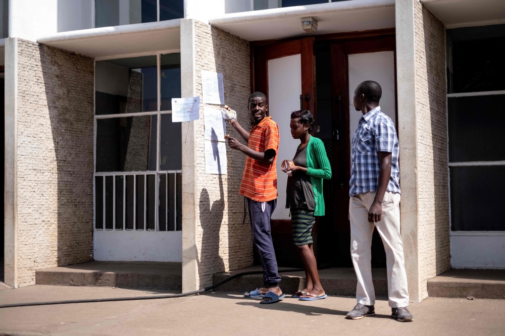 Voters check the polling station results posted outside a building in Harare’s suburb of Mbare on Tuesday, the day after people went to the polls in general election. — AFP
