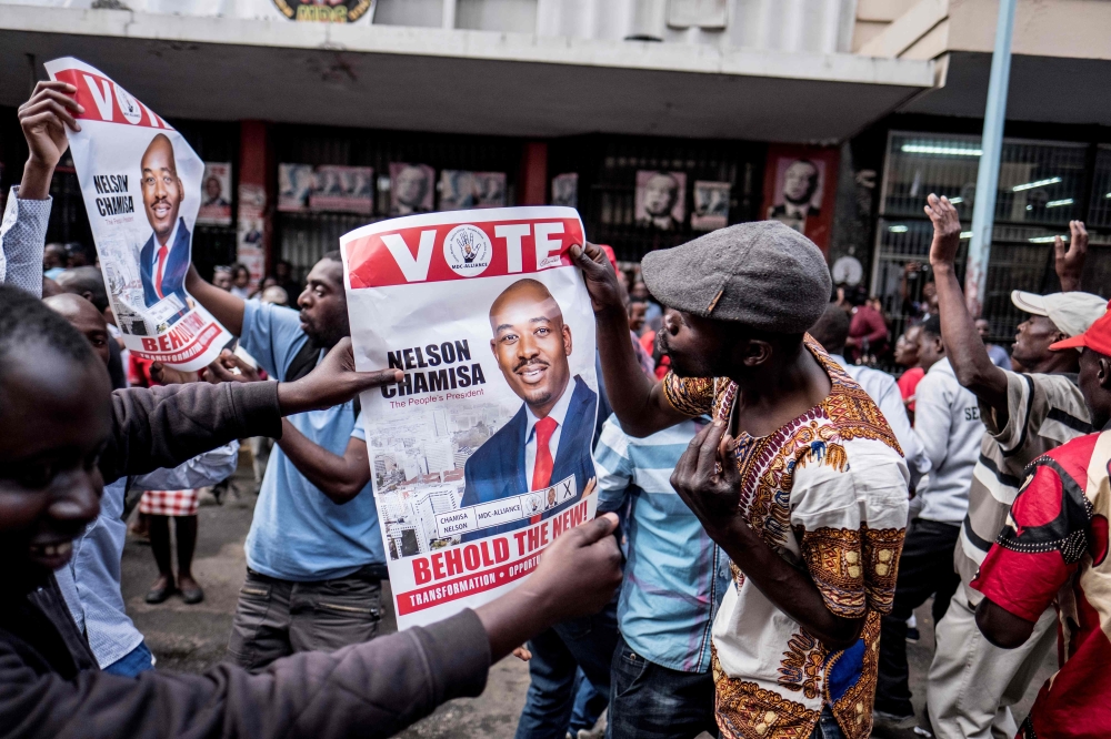 Supporters of Zimbabwean opposition MDC Alliance party leader Nelson Chamisa hold his campaign posters as they gather outside the MDC Alliance’s headquarters in Harare on Tuesday. — AFP