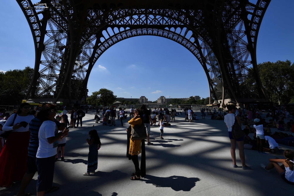 Tourists gather under the Eiffel Tower in Paris on Thursday. — AFP