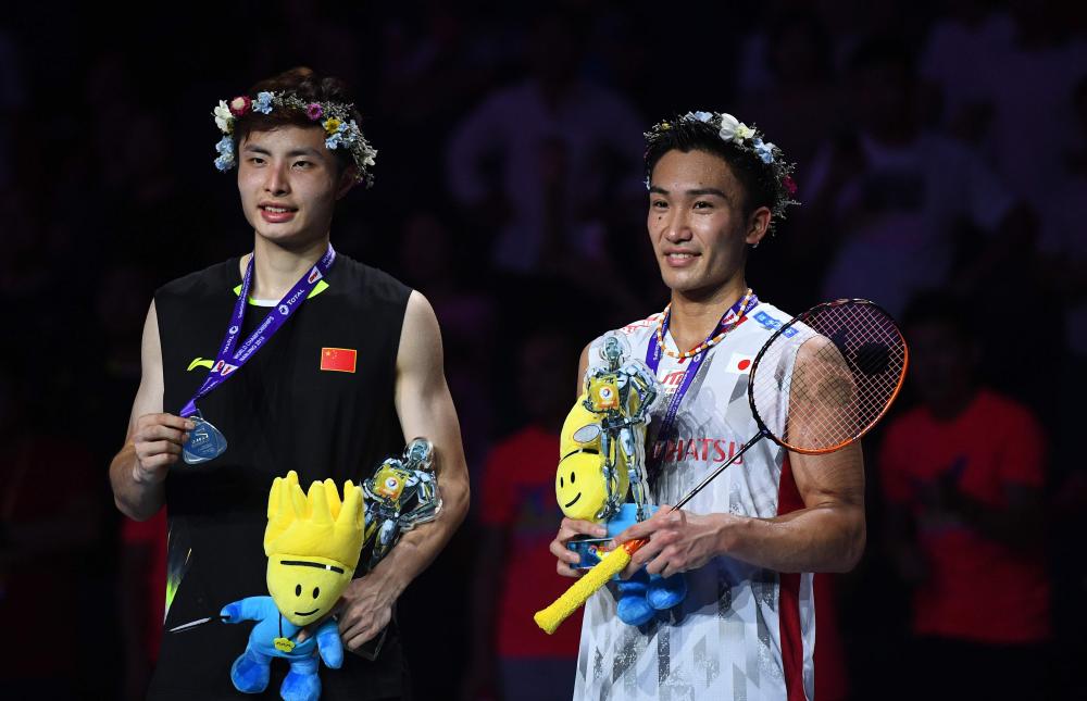Kento Momota of Japan (R) celebrates on the podium after defeating Shi Yuqi (L) of China in the men’s singles final of the Badminton World Championships in Nanjing, China, Sunday. — AFP