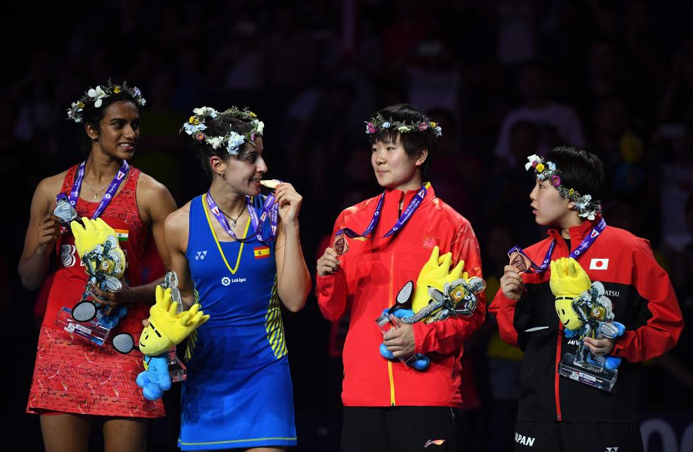 Kento Momota of Japan (R) celebrates on the podium after defeating Shi Yuqi (L) of China in the men’s singles final of the Badminton World Championships in Nanjing, China, Sunday. — AFP